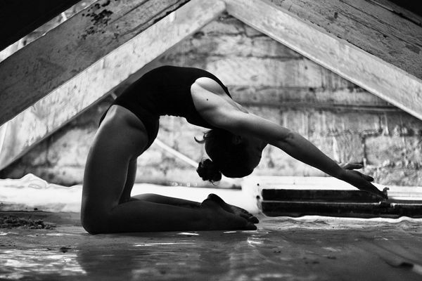 Woman performing a controlled yoga movement in a minimalist space.